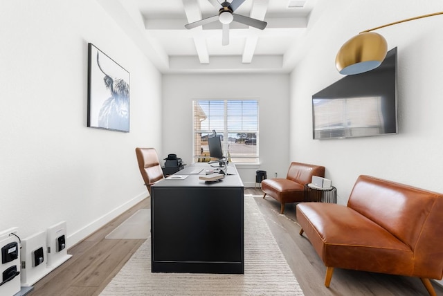 office area featuring light wood-style flooring, a ceiling fan, baseboards, beamed ceiling, and coffered ceiling