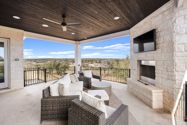 view of patio with ceiling fan and an outdoor living space with a fireplace