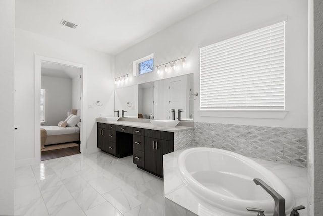 full bath with double vanity, a garden tub, visible vents, a sink, and marble finish floor