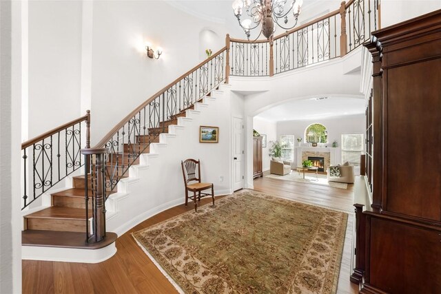 10005 Cormorant Cv, Austin, TX 78730 - foyer entrance with arched walkways, a towering ceiling, wood finished floors, stairway, and a warm lit fireplace