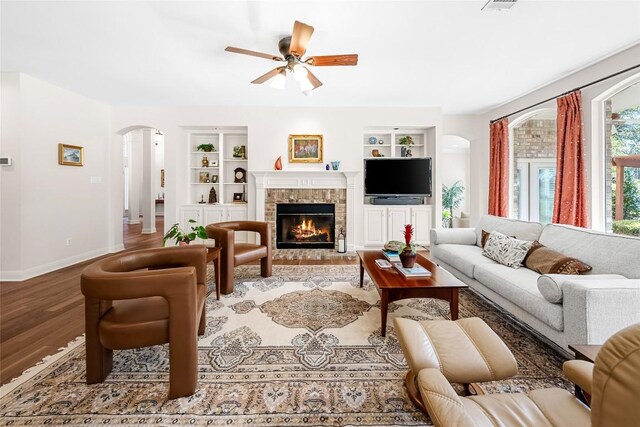 10005 Cormorant Cv, Austin, TX 78730 - living area with built in shelves, arched walkways, baseboards, a ceiling fan, and wood finished floors