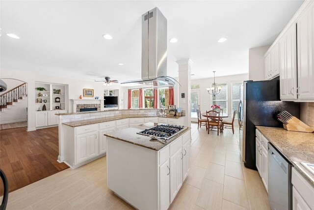10005 Cormorant Cv, Austin, TX 78730 - kitchen featuring appliances with stainless steel finishes, a ceiling fan, a center island, island range hood, and a chandelier