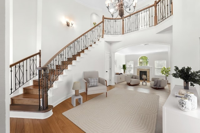 10005 Cormorant Cv, Austin, TX 78730 - stairway featuring a towering ceiling, wood finished floors, arched walkways, a chandelier, and a fireplace