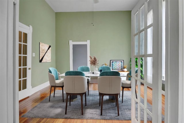 dining area featuring a towering ceiling, baseboards, and wood finished floors