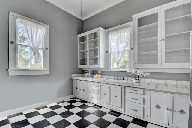 kitchen with glass insert cabinets, white cabinetry, a sink, and light floors