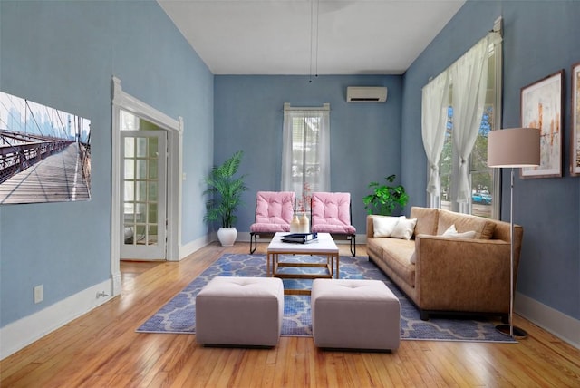 living room with a wall mounted air conditioner, baseboards, and wood-type flooring