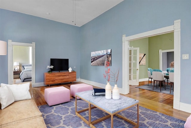 living area with a high ceiling, baseboards, and wood finished floors