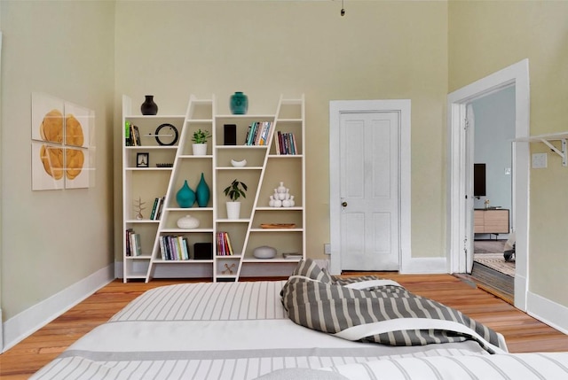 sitting room with baseboards, a high ceiling, and wood finished floors