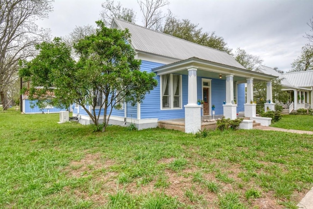 view of front of house with a front lawn, metal roof, and covered porch