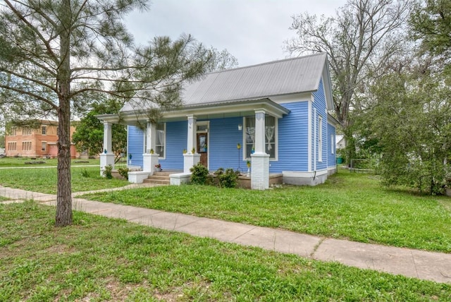 view of front of home with a front lawn, metal roof, and covered porch