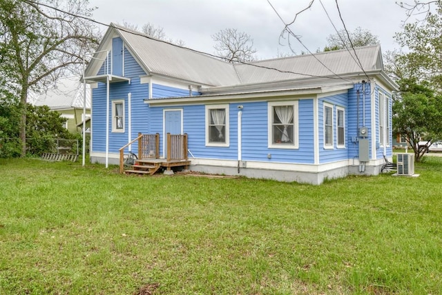 back of property featuring metal roof, fence, and a yard