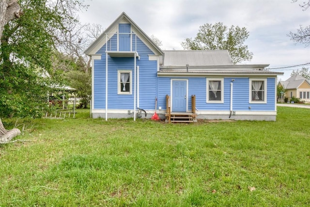 rear view of house featuring metal roof, a yard, and entry steps