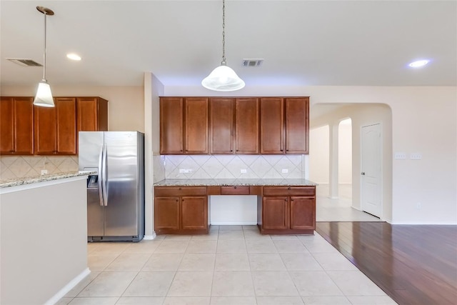 868 Water Hyacinth Loop, Leander, TX 78641 - kitchen featuring stainless steel refrigerator with ice dispenser, arched walkways, tasteful backsplash, decorative light fixtures, and light tile patterned floors