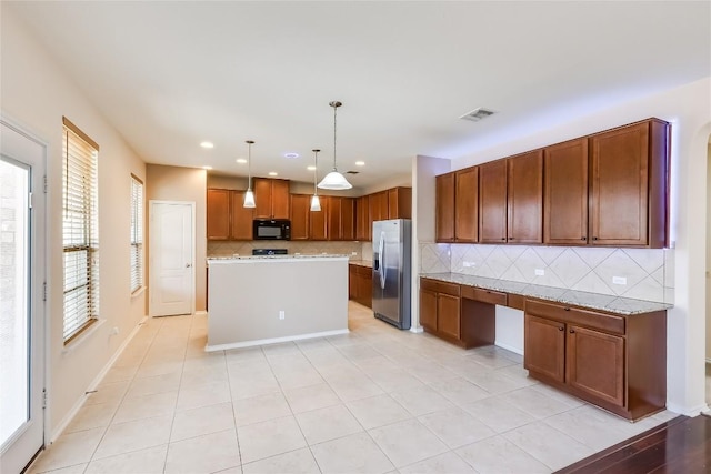 868 Water Hyacinth Loop, Leander, TX 78641 - kitchen featuring black microwave, stainless steel fridge, decorative backsplash, brown cabinetry, and hanging light fixtures