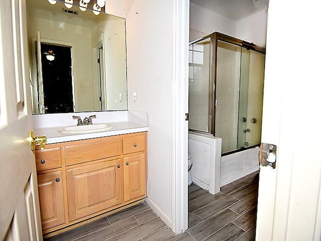 159 Moku Manu Dr, Bastrop, TX 78602 - full bathroom featuring vanity, wood tiled floors, and bath / shower combo with glass door