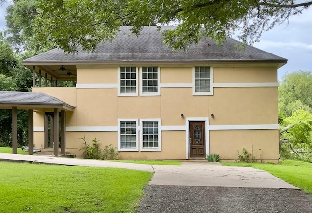 159 Moku Manu Dr, Bastrop, TX 78602 - back of property featuring a lawn, ceiling fan, stucco siding, and a shingled roof