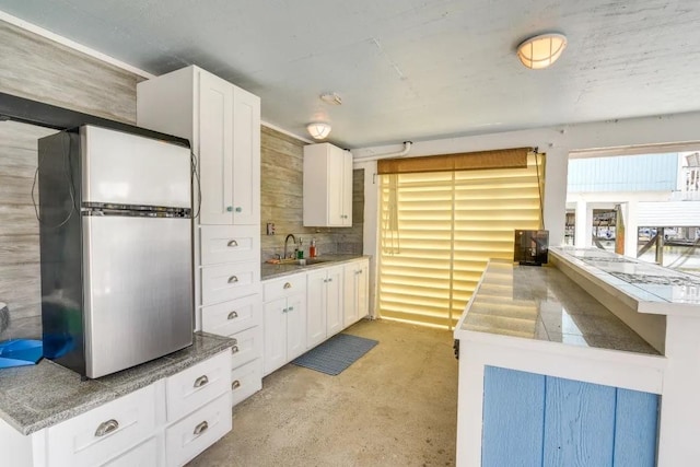 16525 Jamaica Cove Rd, Jamaica Beach, TX 77554 - kitchen featuring white cabinetry, a sink, a peninsula, and freestanding refrigerator