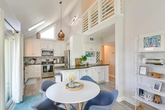 16525 Jamaica Cove Rd, Jamaica Beach, TX 77554 - kitchen featuring tasteful backsplash, stainless steel appliances, dark countertops, visible vents, and light wood-style flooring