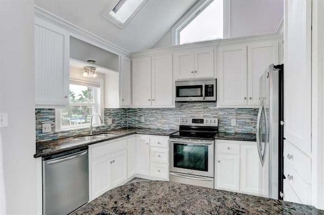 16525 Jamaica Cove Rd, Jamaica Beach, TX 77554 - kitchen with lofted ceiling, a sink, dark stone countertops, and appliances with stainless steel finishes