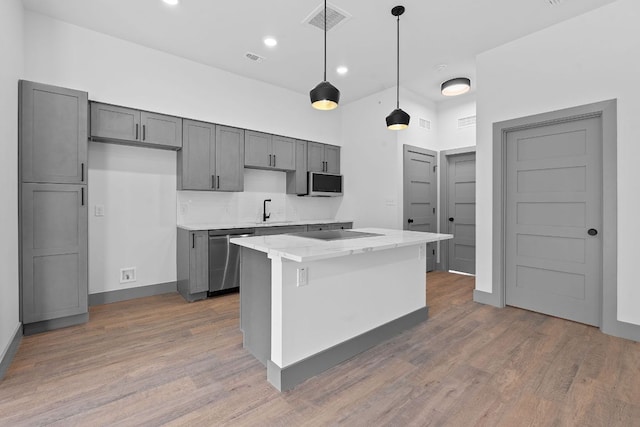 2450 Wickersham Ln Unit 2021, Austin, TX 78741 - kitchen with stainless steel dishwasher, wood finished floors, a sink, tasteful backsplash, and decorative light fixtures