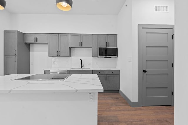 2450 Wickersham Ln Unit 2021, Austin, TX 78741 - kitchen featuring a sink, black electric stovetop, stainless steel microwave, dark wood finished floors, and backsplash