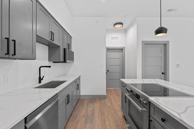 2450 Wickersham Ln Unit 2021, Austin, TX 78741 - kitchen with stainless steel appliances, a sink, light wood-type flooring, decorative backsplash, and pendant lighting