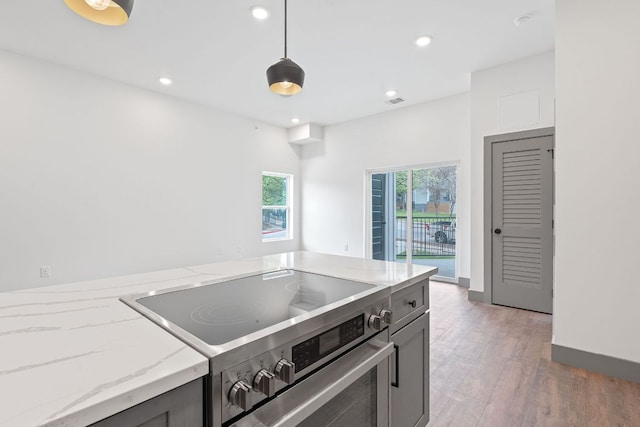 2450 Wickersham Ln Unit 2021, Austin, TX 78741 - kitchen with stainless steel range with electric cooktop, light stone counters, light wood finished floors, recessed lighting, and decorative light fixtures