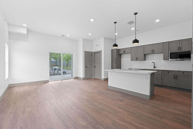 2450 Wickersham Ln Unit 2021, Austin, TX 78741 - kitchen featuring stainless steel microwave, recessed lighting, wood finished floors, decorative backsplash, and a kitchen island