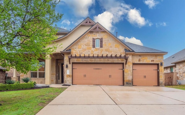 view of front of home featuring stone siding, driveway, a garage, and fence