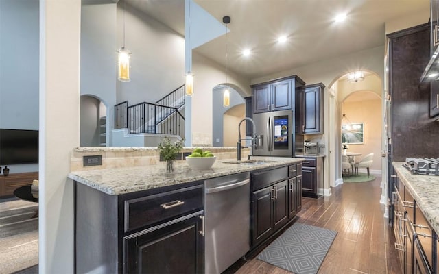 296 Elderberry Rd, Austin, TX 78737 - kitchen with appliances with stainless steel finishes, arched walkways, a sink, dark wood-type flooring, and light stone counters