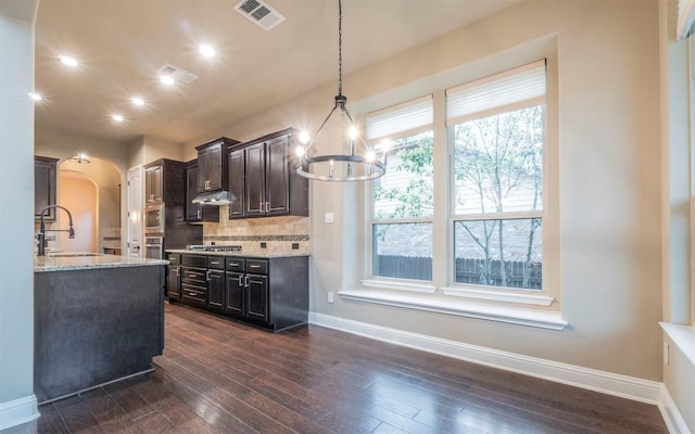 kitchen featuring a sink, a chandelier, stainless steel appliances, visible vents, and arched walkways