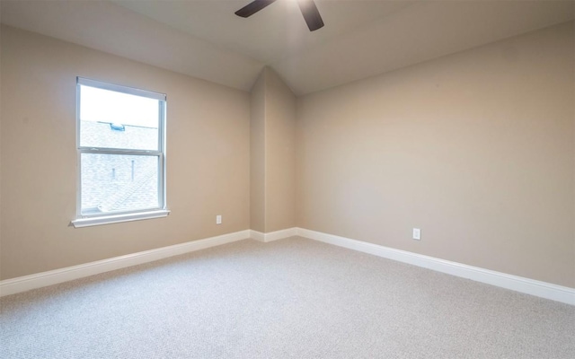 empty room with baseboards, lofted ceiling, ceiling fan, and light colored carpet
