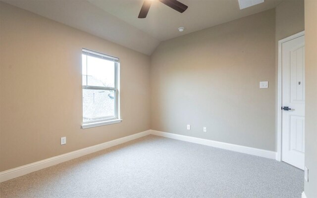carpeted spare room featuring baseboards, ceiling fan, and vaulted ceiling