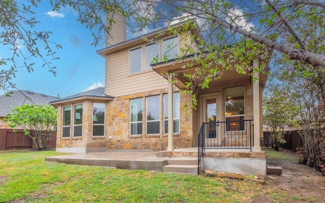 rear view of house with a patio area, a lawn, stone siding, and fence private yard