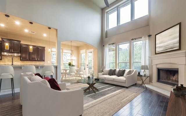 296 Elderberry Rd, Austin, TX 78737 - living room featuring dark wood finished floors, a towering ceiling, arched walkways, and a fireplace with raised hearth