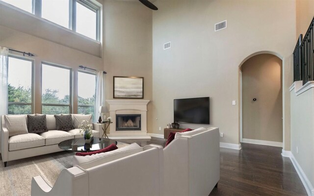 living room featuring arched walkways, baseboards, dark wood-style floors, and visible vents