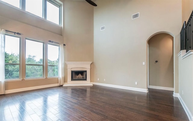 296 Elderberry Rd, Austin, TX 78737 - unfurnished living room featuring a high ceiling, dark wood-style floors, arched walkways, plenty of natural light, and baseboards