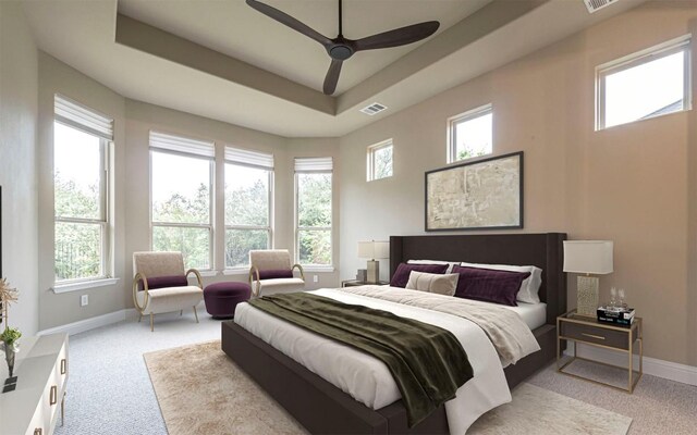 carpeted bedroom featuring a tray ceiling, baseboards, ceiling fan, and visible vents