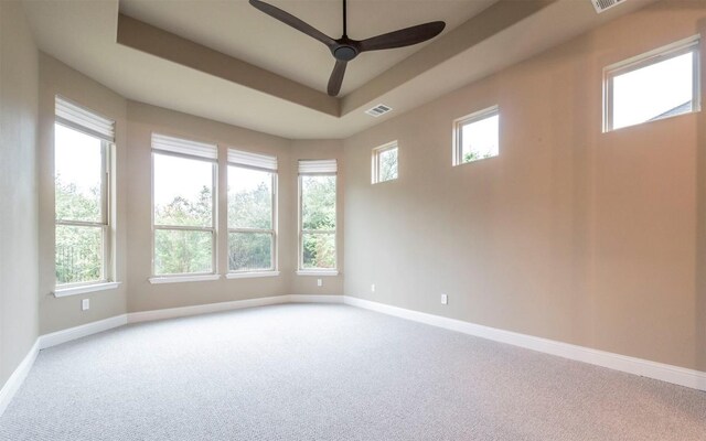 empty room featuring visible vents, baseboards, a ceiling fan, carpet floors, and a tray ceiling