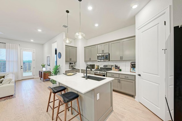 11808 Dillon Falls Dr, Austin, TX 78747 - kitchen with stainless steel appliances, gray cabinetry, a breakfast bar, tasteful backsplash, and recessed lighting