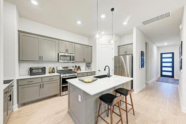 11808 Dillon Falls Dr, Austin, TX 78747 - kitchen with stainless steel appliances, gray cabinetry, tasteful backsplash, light wood finished floors, and recessed lighting