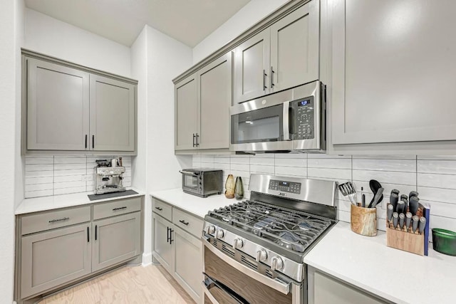 11808 Dillon Falls Dr, Austin, TX 78747 - kitchen with appliances with stainless steel finishes, gray cabinets, tasteful backsplash, and light countertops