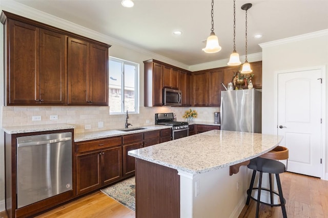 231 Tradinghouse Creek St, Georgetown, TX 78633 - kitchen with appliances with stainless steel finishes, a sink, a kitchen island, light wood-style flooring, and decorative backsplash