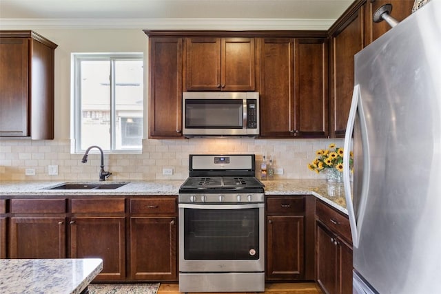 231 Tradinghouse Creek St, Georgetown, TX 78633 - kitchen with stainless steel appliances, a sink, backsplash, light stone counters, and crown molding