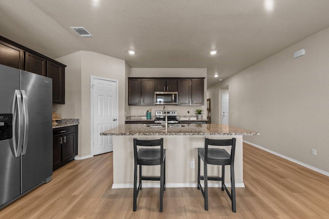 8517 Cantera Ridge Rd, Temple, TX 76502 - kitchen with appliances with stainless steel finishes, light wood finished floors, light stone countertops, a kitchen island with sink, and baseboards