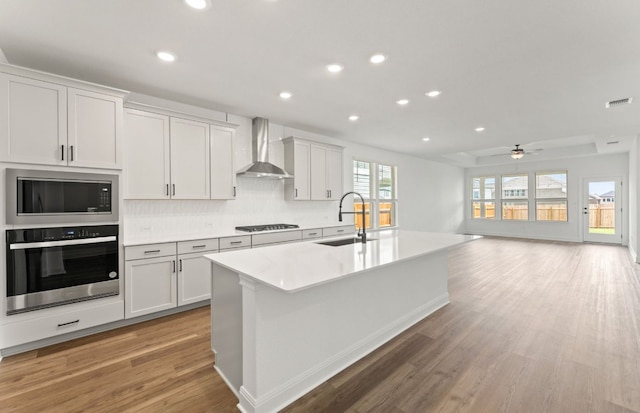 417 Singing Dove Way, Liberty Hill, TX 78642 - kitchen with oven, wall chimney exhaust hood, gas stovetop, a center island with sink, and light wood-style floors