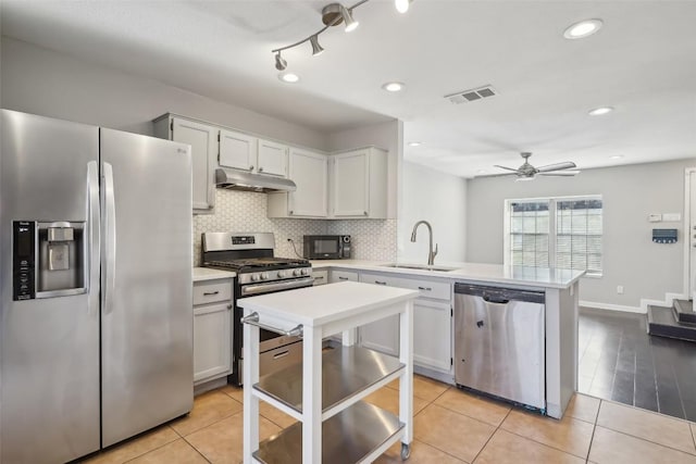 11404 Walnut Ridge Dr Unit 5, Austin, TX 78753 - kitchen featuring stainless steel appliances, a sink, a peninsula, under cabinet range hood, and light countertops