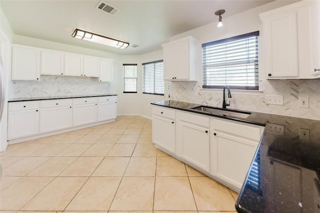 115 Hummingbird Ct, Cedar Creek, TX 78612 - kitchen with a sink, decorative backsplash, white cabinetry, light tile patterned floors, and dark stone countertops