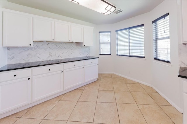 115 Hummingbird Ct, Cedar Creek, TX 78612 - kitchen with dark countertops, plenty of natural light, white cabinetry, and light tile patterned floors