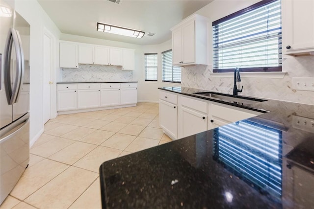 115 Hummingbird Ct, Cedar Creek, TX 78612 - kitchen with a sink, backsplash, freestanding refrigerator, light tile patterned floors, and white cabinetry